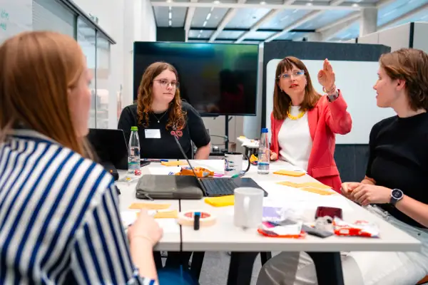 Katharina Hopp im Gespräch mit drei Frauen bei einem Business-Meeting im modernen Konferenzraum.
